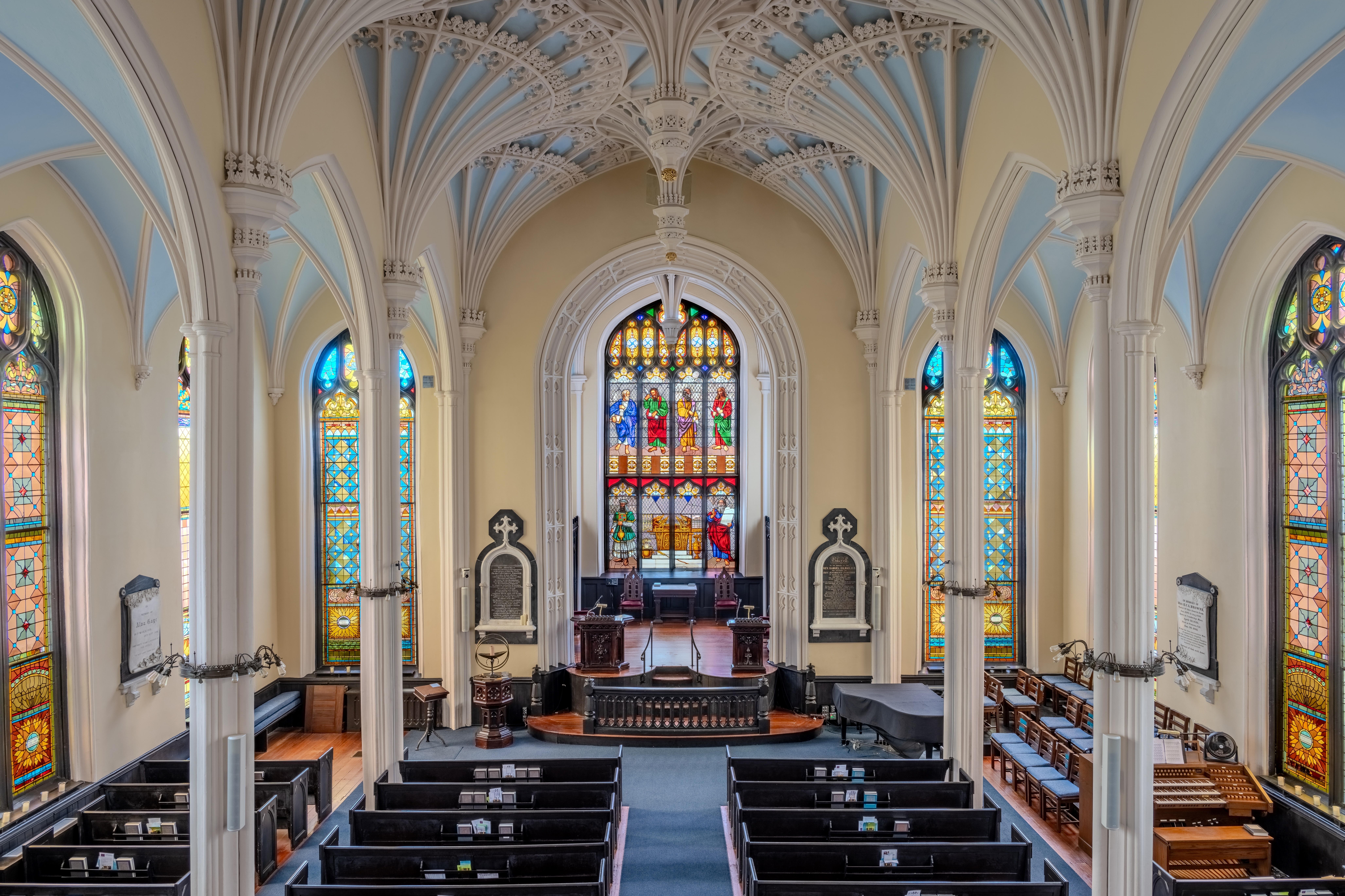 Interior of a church with elegant arches and vibrant stained glass windows, possibly The Unitarian Church in Charleston.